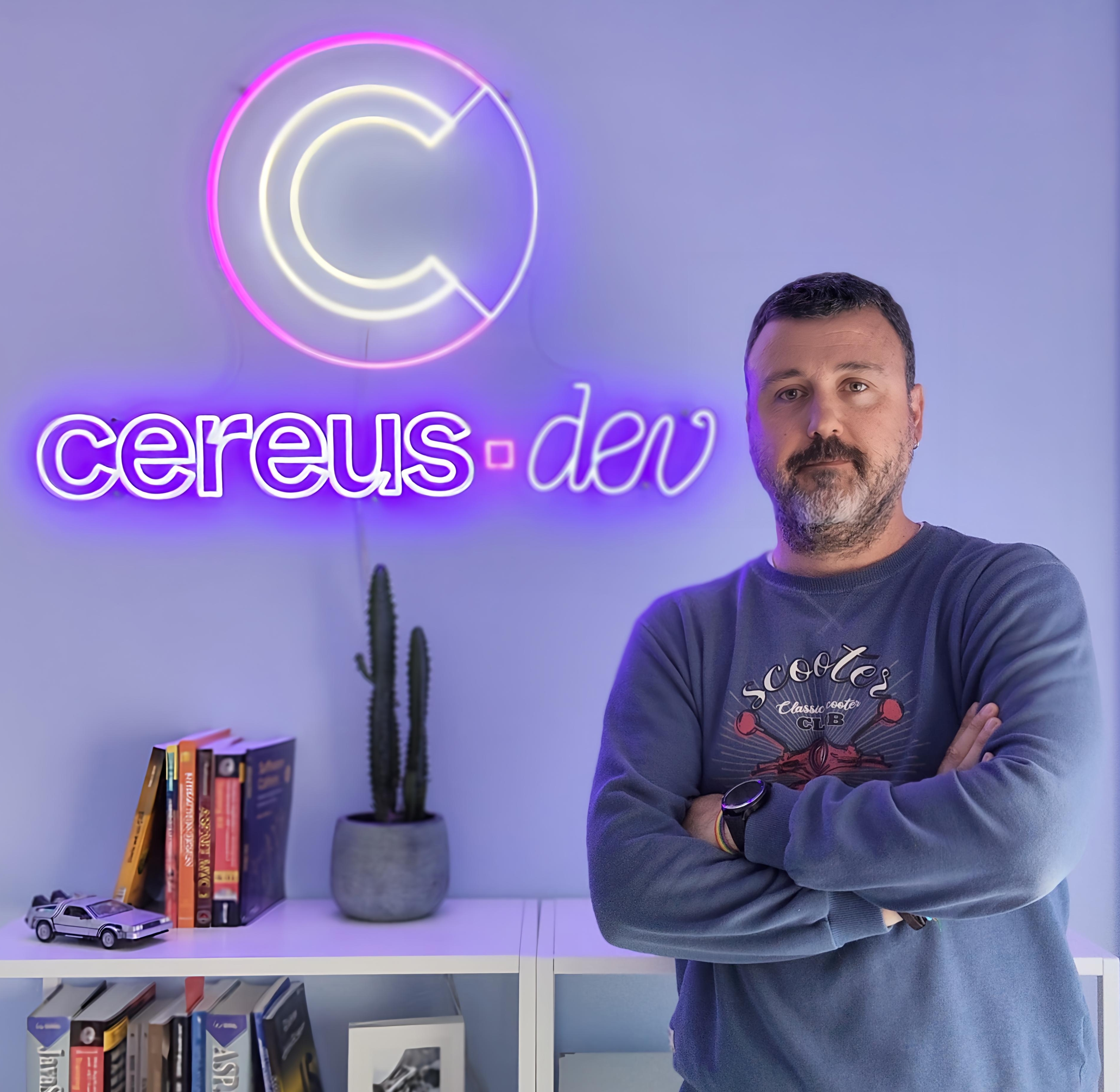 Carlos Navarro, fundador de cereus.dev, ante el rótulo de neón de la marca